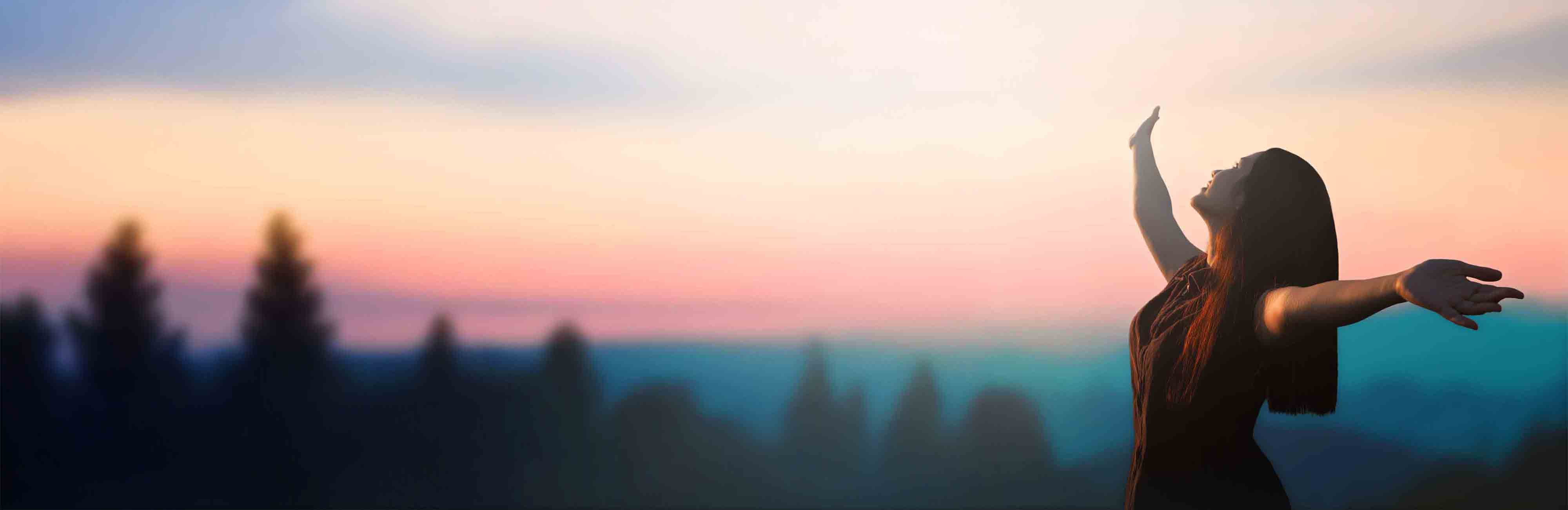 Happy woman raised hand on blurred mountain sunrise background.