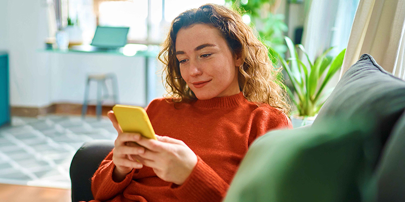 Woman on the couch looking at her phone.